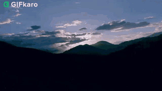 the sun is shining through the clouds over the mountains at sunset