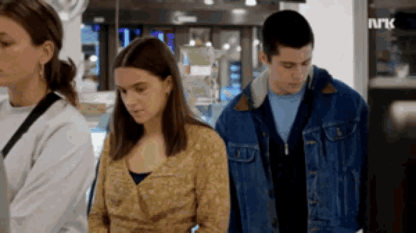 a man and a woman are standing next to each other in front of a sign that says nrk