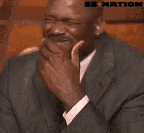 a man in a suit and tie is laughing with a sb nation logo behind him