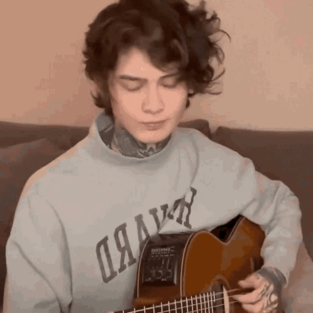 a young man playing a guitar wearing a sweatshirt that says dawn