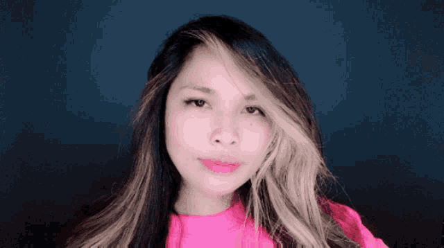 a woman with long hair and a pink shirt is smiling