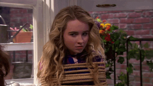 a young girl is tied up with a rope and looking at the camera .