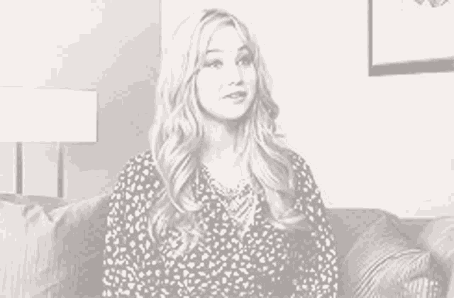 a woman is sitting on a couch in a room with a lamp .