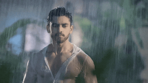 a man with a beard is standing in the rain without a shirt on