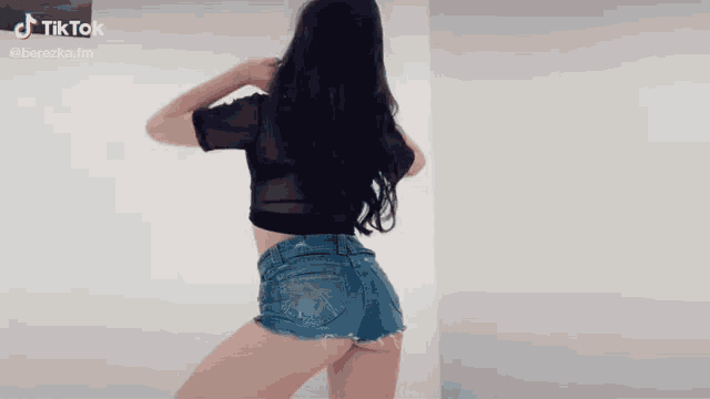a woman in denim shorts and a black top is dancing
