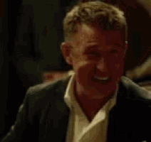 a man in a suit and white shirt is smiling and looking at the camera