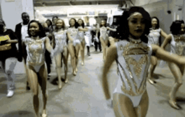a group of women in white and gold leotards are dancing .