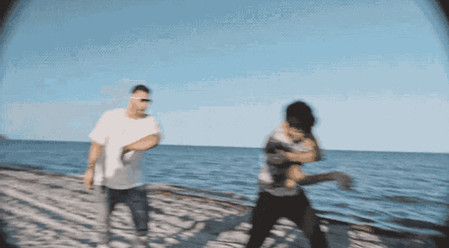 two men are dancing on the beach near the ocean