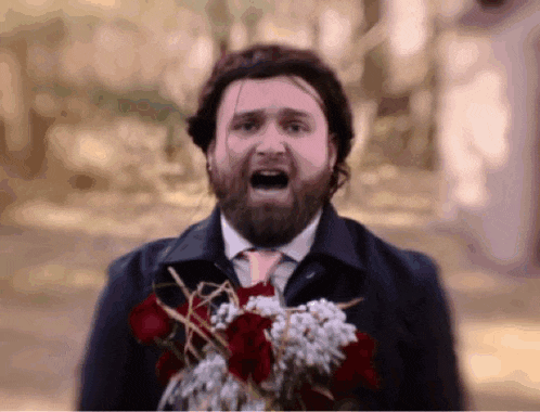 a man in a suit and tie is holding a bouquet of flowers
