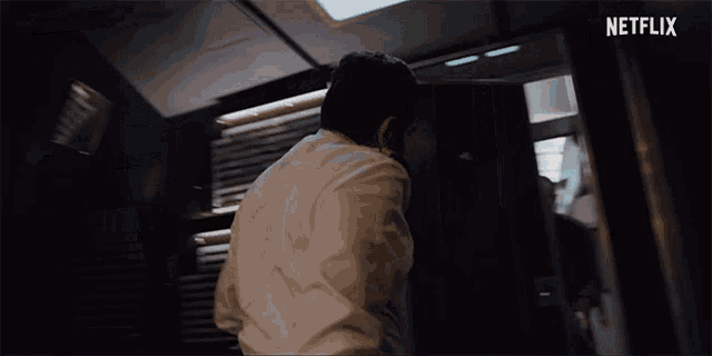 a man in a white shirt is standing in a dark room with a netflix logo in the corner