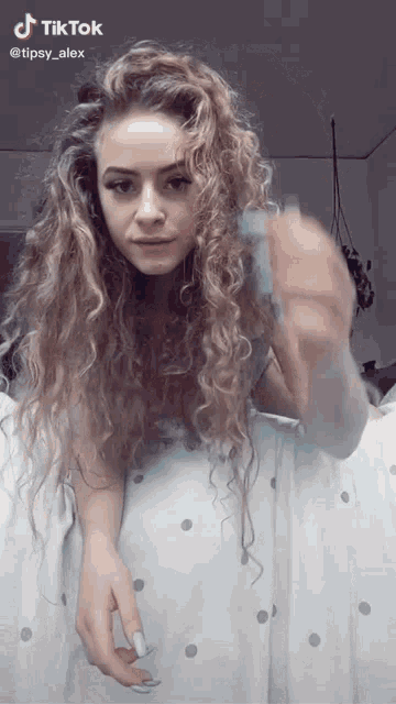 a woman with long curly hair is laying on a bed with a tiktok watermark