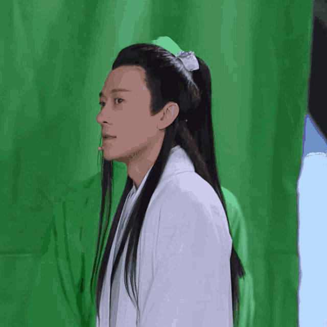 a man with long hair wearing a white shirt and a green headband