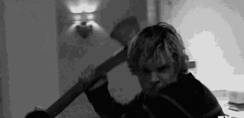 a black and white photo of a man holding an axe in a room .