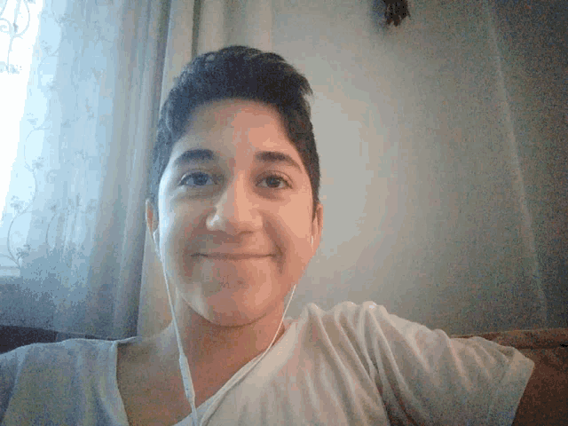a young boy wearing earbuds smiles for the camera