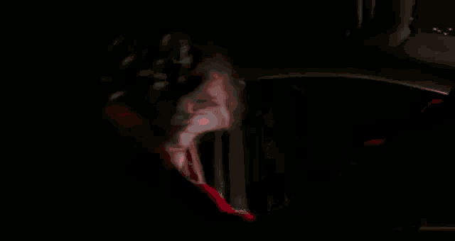a woman in a red sweater is driving a car at night and looking out the window .