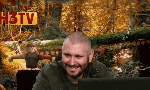 a man sitting in front of a h3tv sign