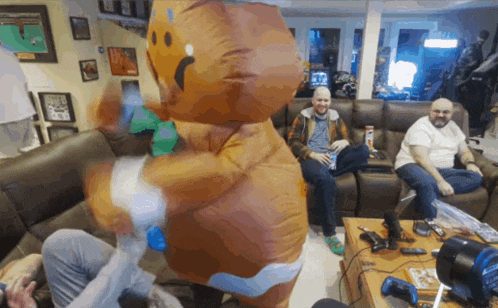 a group of men are playing video games in a living room with an inflatable gingerbread man in the middle