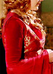 a woman wearing a red dress with gold embroidery