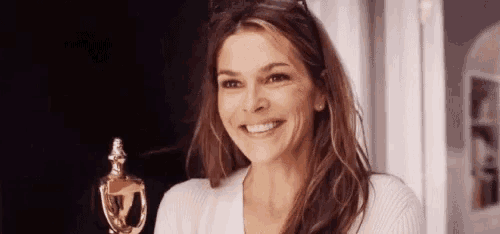 a woman is smiling while holding a trophy and looking at the camera .