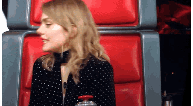 a woman sitting in a red chair with a bottle of water in her hand