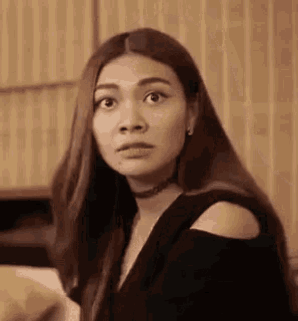 a woman with long hair is looking at the camera with a surprised look on her face .