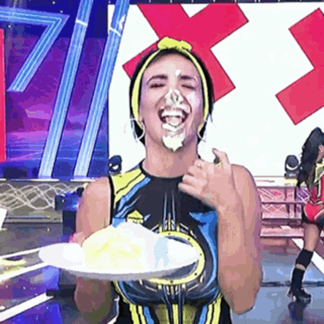 a woman is holding a plate of food in front of her face .