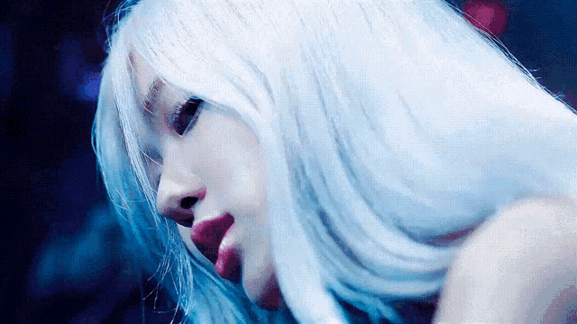 a woman with white hair and red lips looks down